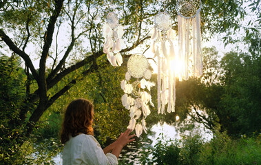 girl in light dress and dream catchers hanging on tree outdoor. Summer background. ethnic Shaman...