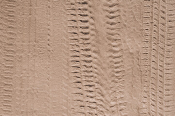 Background, texture of the uneven surface of traces, imprints from wheels, car tires, vehicles on a sandy road. Close-up photo, top view, pattern design concept.