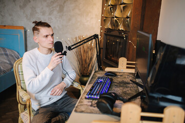 Young man makes a podcast audio recording at home. Man using pc and two professional microphones....