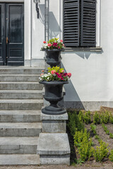 black ornate flower pots filled with flowers stand on a concrete stone