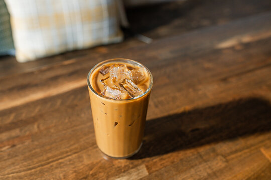 Small glass of iced coffee with ice on a table.