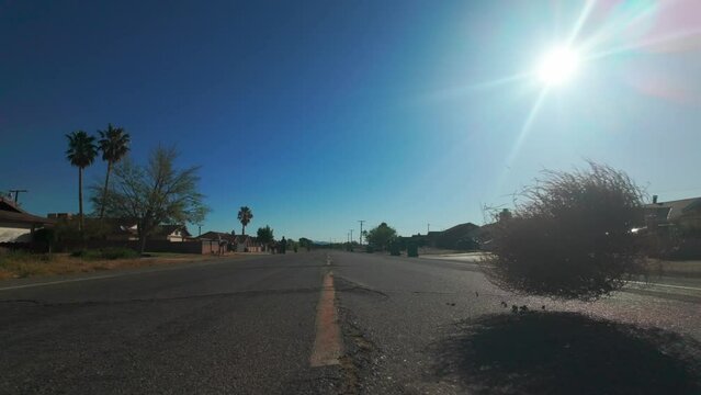 Slow motion footage of tumbleweed flying across a road passing through houses on a sunny day