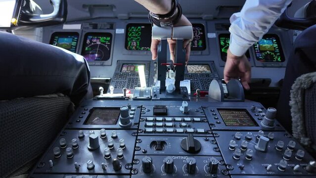 Close-up view of two  white pilots doing routine labors in a modern cockpit jet. Real time flight. Camera between both pilots. Daylight. 4K 60FPS.