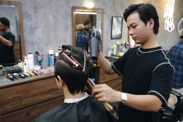 Barber blow drying wet hair of client