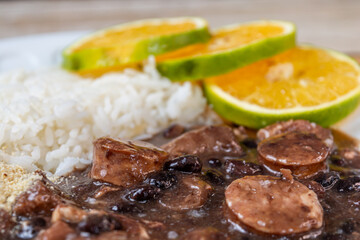 Traditional Brazilian feijoada served with white rice and fresh orange slices, a hearty and flavorful black bean stew with mixed meats.