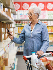 Senior woman checking supermarket products using her smartphone