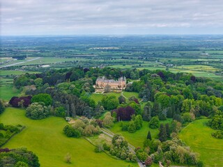 Aerial view of Waddesdon Manor atop a hill surrounded by lush green fields in Buckinghamshire.