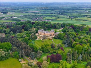 Aerial view of Waddesdon Manor atop a hill surrounded by lush green fields in Buckinghamshire.