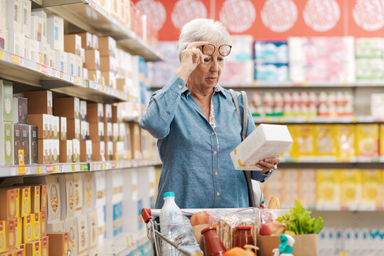 Senior woman with vision problems reading information on a product package at the supermarket