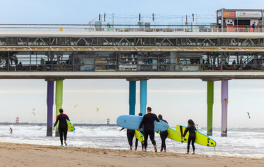 Surfers on Scheveningen Beach in the Netherlands with the pier in the background