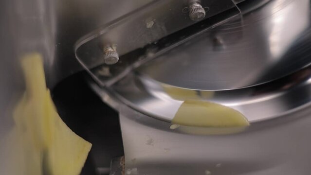 Close-up shot of a stainless steel cheese cutter slicing through cheese.