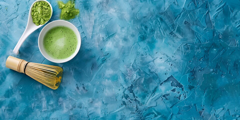 A blue surface with a bowl containing and a bamboo whisk on the side A bowl of matcha powder sits...