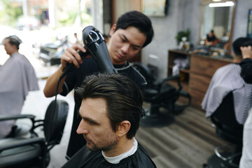 Hairdresser blow drying freshly cut hair of client