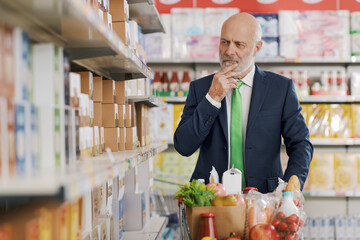 Businessman looking for products on the store shelves at the supermarket