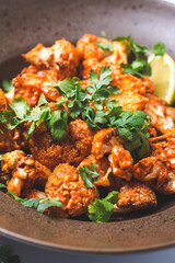 Baked cauliflower in tomato sauce with herbs, white background.