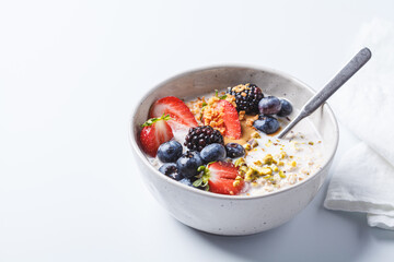 Oatmeal with fresh berries and nuts, white background. Healthy breakfast concept.