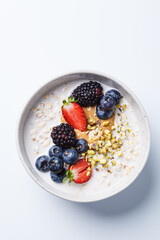 Oatmeal with fresh berries and nuts, white background. Healthy breakfast concept.