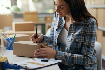 Woman writing a shipping address on a delivery box
