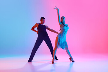 Art in Motion. Two young people, man and woman, ballroom dancers display their skills in neon...