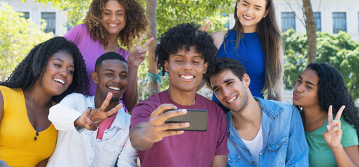 Happy latin american and hispanic and african american and caucasian young adults taking selfie...