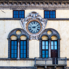 Ancient clock on the palace facade in Lucca's San Michele square.