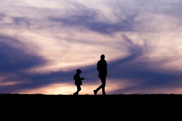 Fototapeta premium Silhouette of a parent and child against the sky