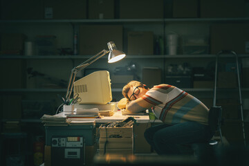 Nerd guy falling asleep at his desk in the garage