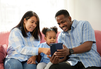 mixed race family using tablet online video call and taking selfie on sofa