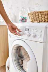 African American woman adjusting a button on a washing machine while doing laundry in a bathroom.