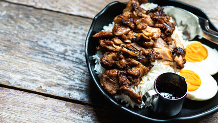 Grilled chicken and boiled eggs on rice are placed on a wooden table. ,grilled chicken on rice