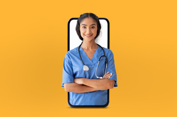 Indian lady medical professional in blue scrubs stands confidently with arms crossed, appearing...
