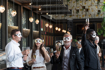 Group of diverse friends toasting with clinking champagne glasses at funny and happy Christmas and new year mask party atmosphere. Holiday celebrate and nightlife lifestyle concept