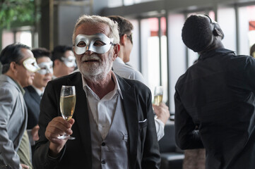 Group of diverse friends toasting with clinking champagne glasses at funny and happy Christmas and new year mask party atmosphere. Holiday celebrate and nightlife lifestyle concept