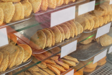 Many empanadas baked on a counter. Blank labels to write the ingredients of the empanadas. Traditional Latin American food.