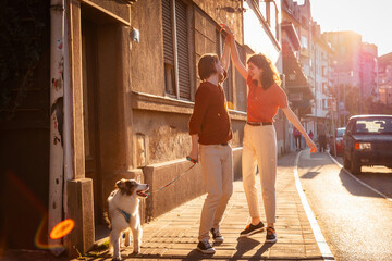 Romantic date of man and woman dancing on the street. Man and woman walking with dog Aussie. Sunset...