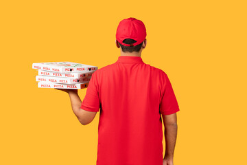 A man wearing a red uniform is standing, holding a box of pizza. The man appears to be delivering the pizza to a customer. The box is prominently displayed in his hands.