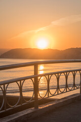 Obraz premium Sunset on the beach in the City of Santos, Brazil. The handrail railing of the bridge over the water channel.