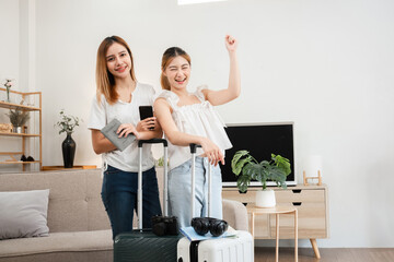 Happy Asian women ready for travel with passports and luggage in living room. Indoor concept of...
