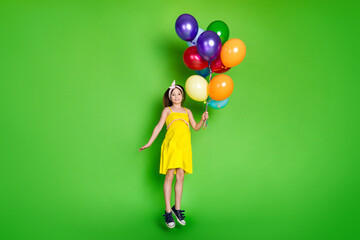 Full length photo of girlish pretty little lady dressed yellow outfit jumping rising balloons empty...