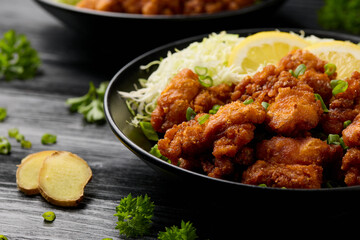 Japanese Fried crispy Chicken Karaage in black bowl with rice and cabbage