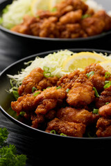 Japanese Fried crispy Chicken Karaage in black bowl with rice and cabbage