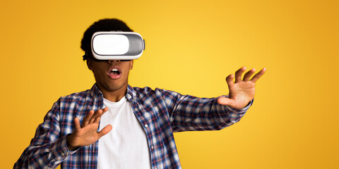 Guy experiencing with VR goggles, playing video games over yellow background