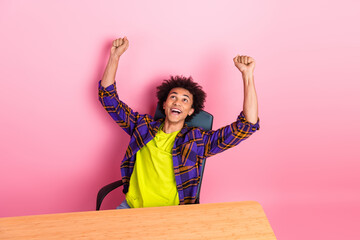 Photo of excited guy worker sit table raise fists up winning isolated pastel color background