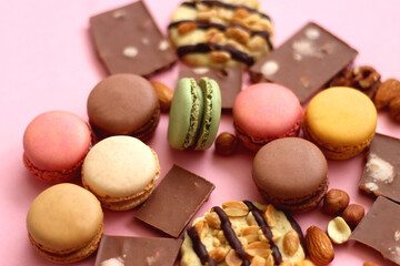 Pastel macarons, almond chocolate, peanut butter cookies and various nuts on bright pink background. Selective focus.