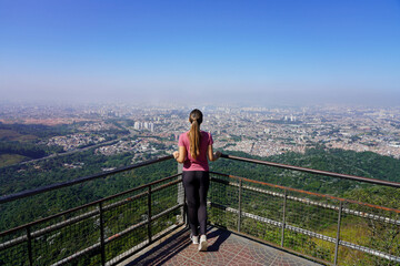 Young woman enjoying cityscape of Sao Paulo from Jaragua Peak the highest mountain in the Brazilian...