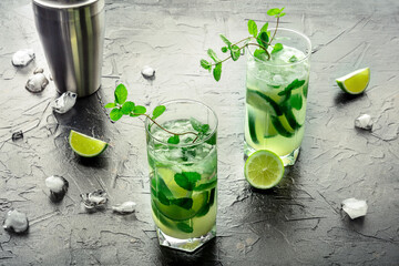 Mojito cocktail. Summer cold drink with lime, fresh mint, and ice. Cool beverage on a black slate...