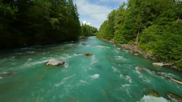 FPV drone flight over the fast moving river with rapids, close to the water.