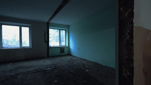 Entering the doorway in the old building under the demolition process. Empty room with two windows.