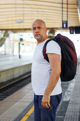 Man traveler waiting on station waiting for a train. Railroad transport and booked. The concept of a man traveling alone.