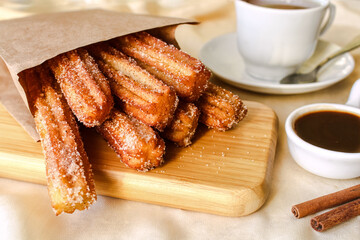 Churros. Churros with hot chocolate sauce, sugar and cinnamon.  Churros on a plate with hot chocolate sauce. A traditional Spanish dessert. Street fast food.